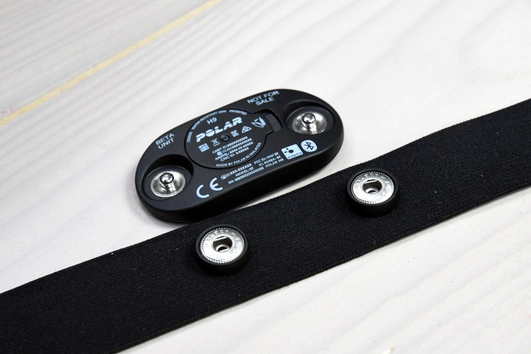 Fotografia 8. Przykładowy pulsometr z pasem piersiowym marki Polar. Widoczne zatrzaski pełniące rolę mechanicznego mocowania urządzenia oraz podłączenia do elektrod EKG