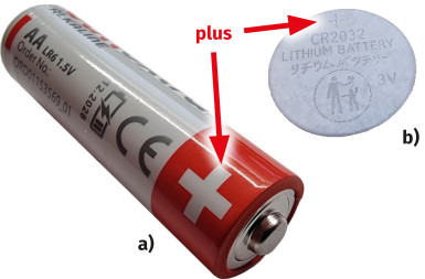 Fotografia 4. Oznakowanie biegunowości a) na ogniwie AA (R6) b) na ogniwie CR2032