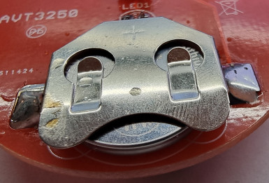 Fotografia 3. Bateria CR2032 zamontowana w slocie tworzonym przez powierzchnię płytki PCB z przylutowaną do niej, dołączoną do zestawu, profilowaną blaszką